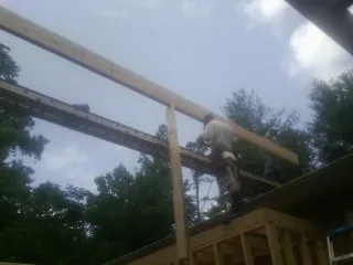 Carpenter setting a ridge beam over a new addition frame — Ice Dam Removal by Roofing Brothers in Churdan