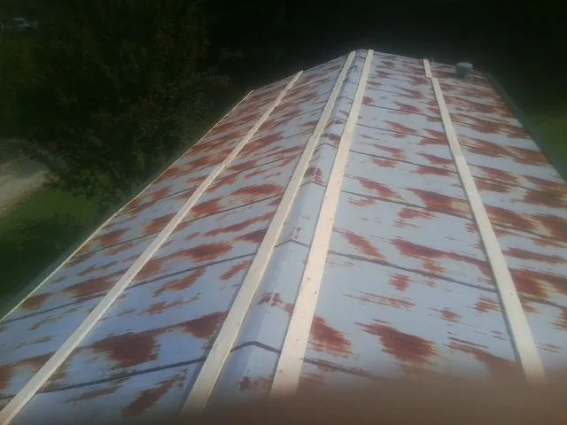 Rusted metal roof panels with new wood purlins before replacement — Storm Damage Roof Repair in Churdan by Roofing Brothers