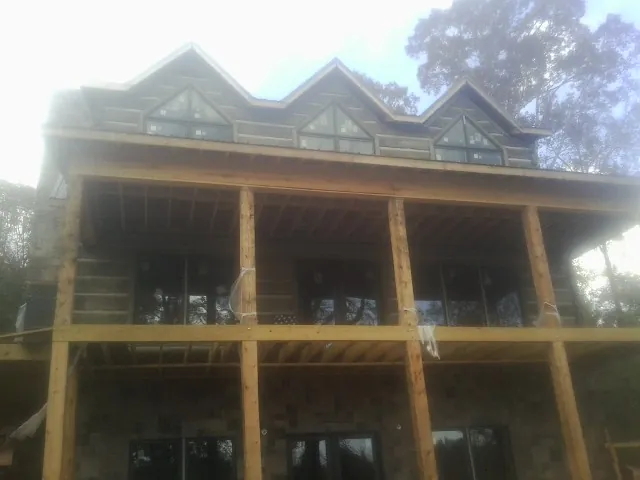 Dormers and porch framing on a large log home under construction — Roof Coating work by our crew in Churdan