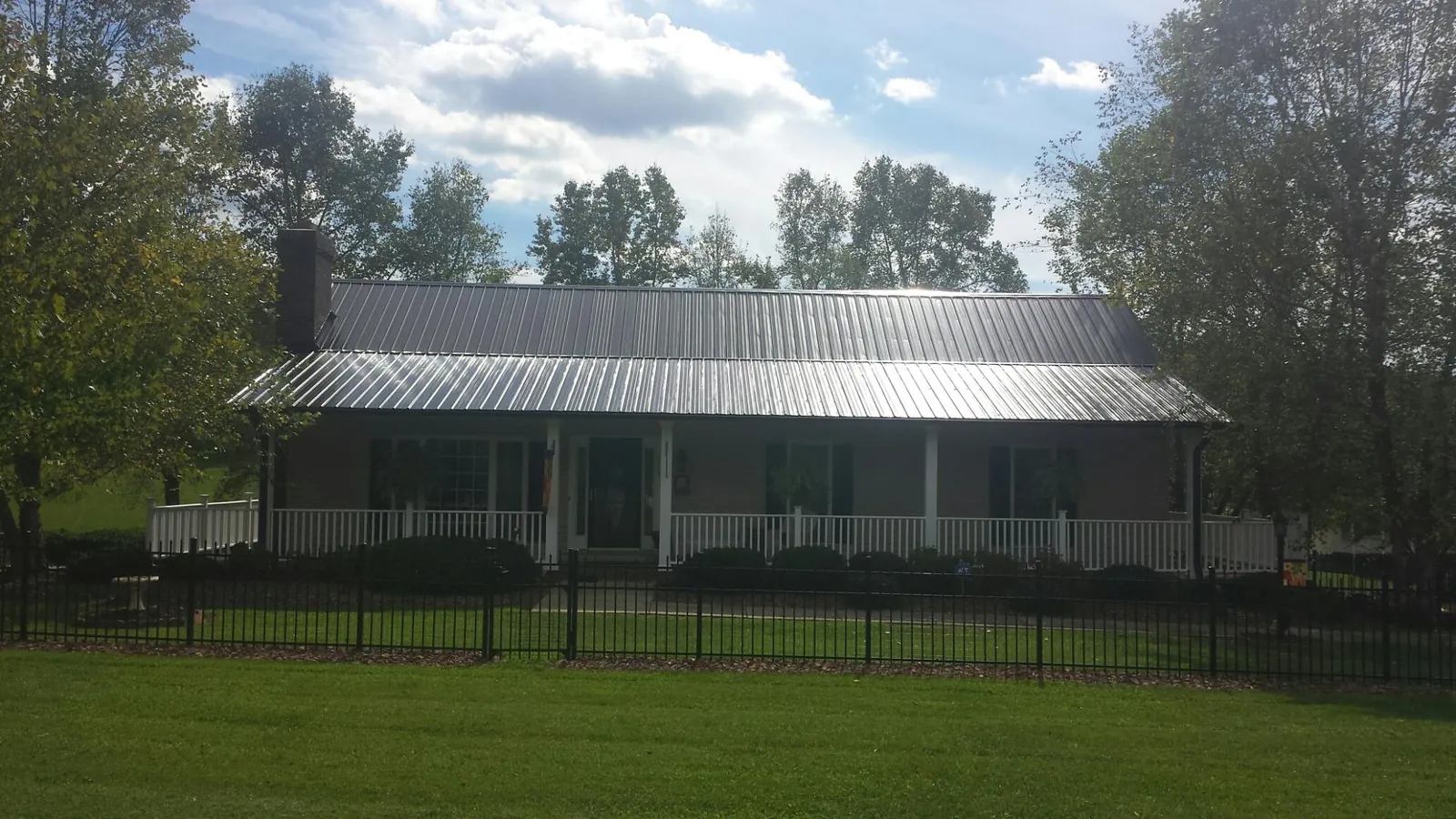 Gray metal roof on a brick ranch with a full width front porch — Gutter Guard Installation work by our crew in Churdan