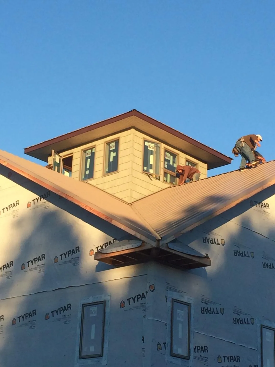 Roofers working around a rooftop cupola on a new metal roof at sunset — Roof Waterproofing in Churdan by Roofing Brothers